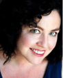 Woman with dark hair and green eyes smiling.