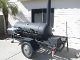 Black smoker on a trailer outdoors.